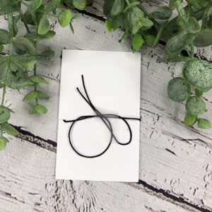 May include: A white card with a black string tied around it in a knot.