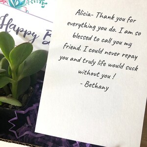 May include: A gift box containing a small succulent plant, purple shredded paper, and a handwritten note. The note reads "Alicia- Thank you for everything you do..." and is signed "- Bethany". A card with floral accents says "Happy E".