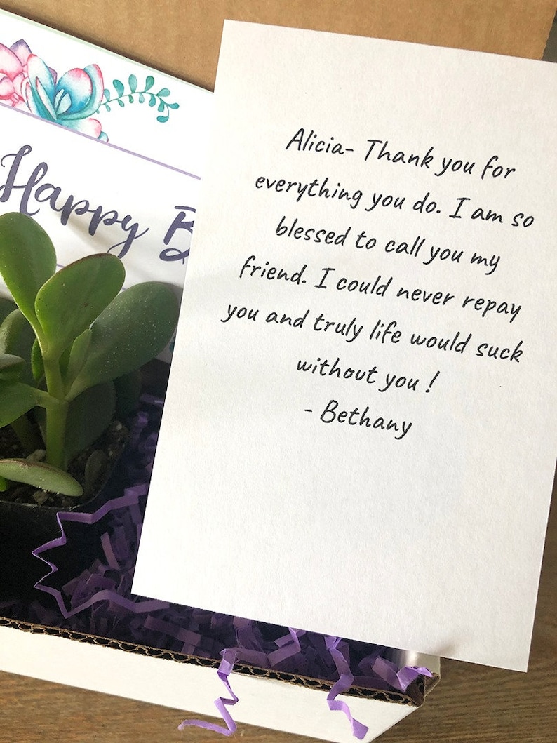 May include: A gift box containing a small succulent plant, purple shredded paper, and a handwritten note. The note reads "Alicia- Thank you for everything you do..." and is signed "- Bethany". A card with floral accents says "Happy E".
