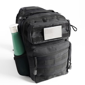 May include: Black tactical sling bag with a zippered pocket and a mesh side pocket. The bag has a US flag patch on the front.