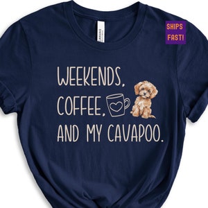 May include: Navy blue t-shirt with the text "Weekends, Coffee, and My Cavapoo." A cartoon image of a brown and white cavapoo dog is next to the text, and a coffee mug with a heart is next to the word "Coffee."
