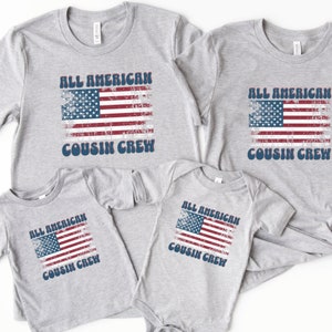 May include: Set of four grey t-shirts with a distressed American flag design and the text "All American Cousin Crew".