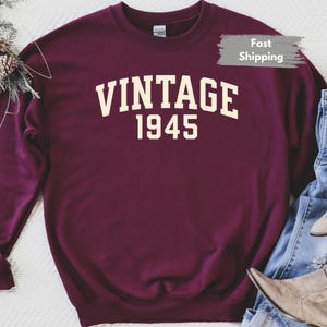 Op de afbeelding: Bordeauxkleurig sweatshirt met witte tekst "Vintage 1945".
