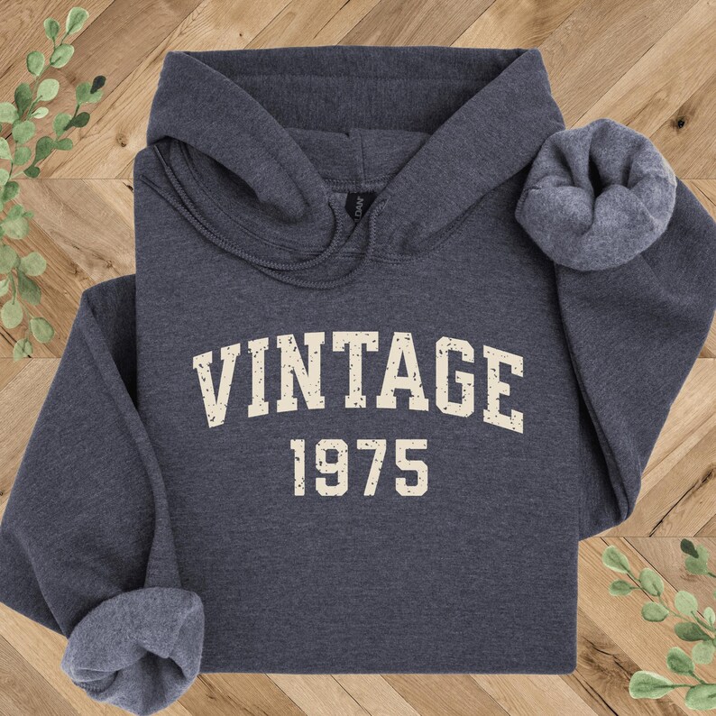 May include: A dark gray hooded sweatshirt with the text "Vintage 1975" printed in white on the front.