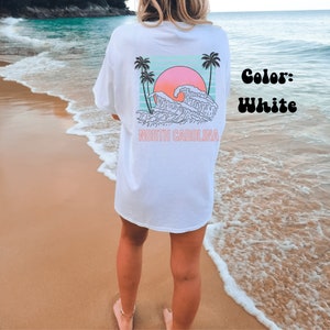 May include: White t-shirt with a graphic of a sunset over waves and palm trees. The text "NORTH CAROLINA" is printed below the graphic.