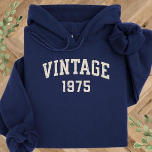 May include: A navy blue hoodie with a white vintage 1975 graphic.
