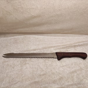 Pode incluir: Uma faca de pão longa, prateada, com borda serrilhada e cabo de madeira marrom.