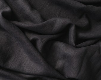 May include: A close-up of a dark gray fabric with a smooth, textured surface. The fabric is draped and folded, creating soft, flowing lines.