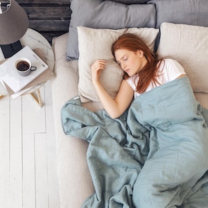 Sleeping women in blue color weighted blanket in the bed