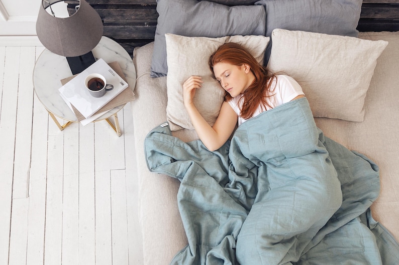 Sleeping women in blue color weighted blanket in the bed