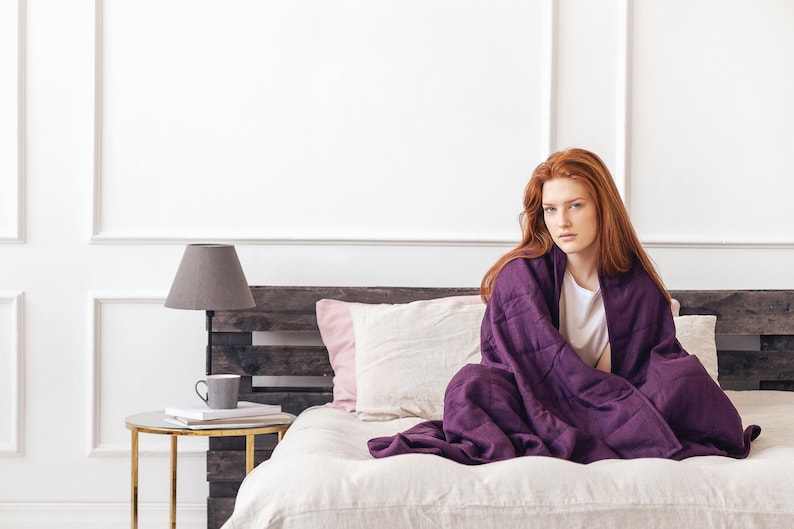 Women are covered by a weighted blanket in purple color