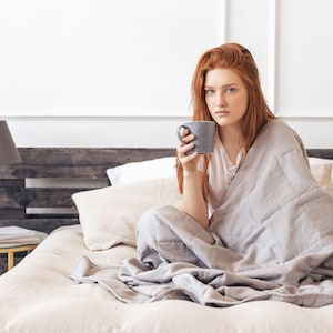 Women covered by a weighted blanket grey color