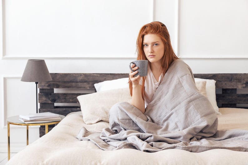Women covered by a weighted blanket grey color