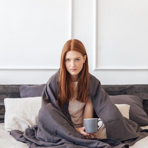 Women are covered by a weighted blanket in grey color