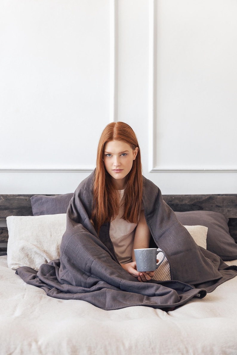 Women are covered by a weighted blanket in grey color