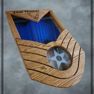 May include: A wooden shadow box with a blue background and a star in the center. The box is engraved with "TSgt Thomas" and the Air Force emblem.