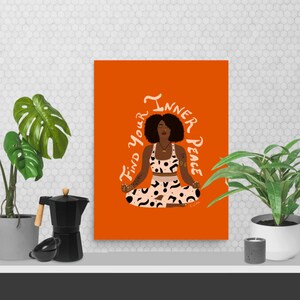 May include: An orange art print featuring a woman in a yoga pose with the text "Find your Inner Peace". The woman is wearing a patterned crop top and leggings. The print is displayed on a white shelf with plants and a coffee maker.