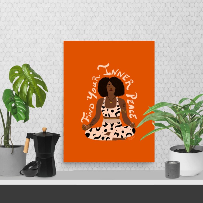 May include: An orange art print featuring a woman in a yoga pose with the text "Find your Inner Peace". The woman is wearing a patterned crop top and leggings. The print is displayed on a white shelf with plants and a coffee maker.