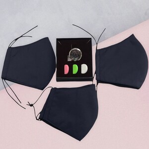 May include: Three black face masks with a small box containing a silver charm and three colorful round inserts.