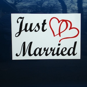 May include: White magnetic sign with black text that reads "Just Married" with two red intertwined hearts.