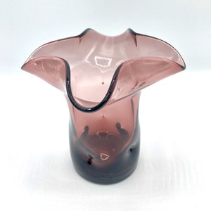 May include: A small, ruffled, purple glass vase with a wide opening and a textured base.