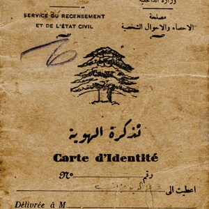 May include: A vintage Lebanese identity card printed on aged, tan paper. The document features the cedar tree emblem, text in French and Arabic including 'REPUBLIQUE LIBANAISE' and 'Carte d'Identit&eacute;', and a handwritten ink mark.