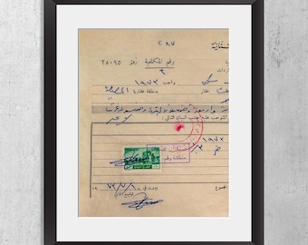 May include: A framed vintage document featuring aged beige paper with handwritten Arabic script in blue and black ink. A green postage stamp is affixed to the center, accompanied by a red circular ink stamp and several handwritten signatures.