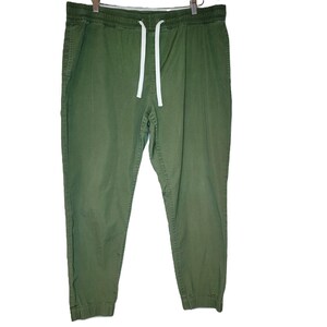 May include: Olive green joggers with an elastic waistband and white drawstring. The pants have two side pockets and elastic cuffs at the ankles. The fabric appears to be a lightweight cotton blend.