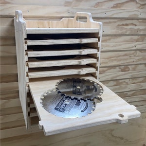 May include: A wooden storage box with a handle and multiple shelves for storing circular saw blades. The box is open and two saw blades are visible, labeled "Freud Super Diablo 8" and "Freud Super Diablo 6".