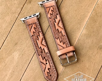 Könnte beinhalten: Zwei hellbraune Leder-Uhrenarmbänder mit geometrischem Design. Die Armbänder haben silberfarbene Anschlüsse und Schnallen. Sie liegen auf einer Holzoberfläche. Das Logo von Wall Leather Co. ist sichtbar.