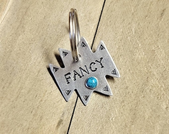 May include: Silver pet tag with a turquoise stone and the word "FANCY" engraved on it. The tag is attached to a silver key ring.