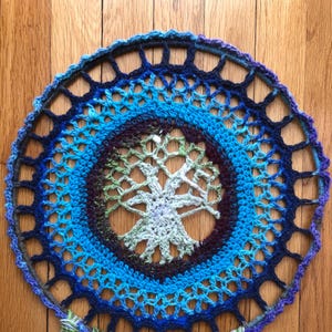 May include: A blue, green, and purple crocheted dreamcatcher with fringe hanging from the bottom.