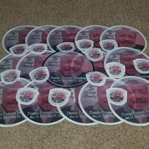 May include: A stack of white paper fans with a black border and a photo of a man. The fans have the text "In loving memory" and "Freddie Orlando Paulding" with dates of birth and death.