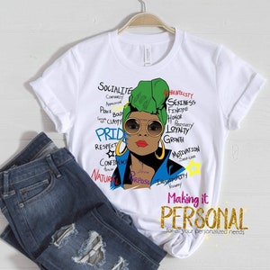 May include: White t-shirt with a colorful illustration of a woman wearing a green head wrap and sunglasses. The illustration is surrounded by words like "Socialite", "Pride", "Respect", "Confidence", "Natural", "Purpose", "Integrity", "Authenticity", "Sexiness", "Finnesse", "Honor", "Loyalty", "Growth", "Motivation", "Self-Love", and "Making it Personal".