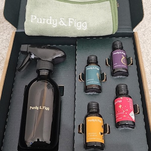 May include: A dark green box set containing a black spray bottle, small glass bottles, and a green cloth. The bottles and spray bottle are labelled "Purdy & Figg". The box has the text "THREE SIMPLE STEPS".