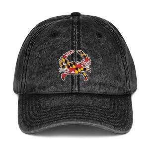 May include: A black vintage washed denim baseball cap with an embroidered Maryland state flag crab design.