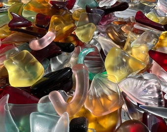 May include: A collection of colorful, translucent glass pieces in various shapes and sizes. The pieces are arranged in a bowl and appear to be made of sea glass.