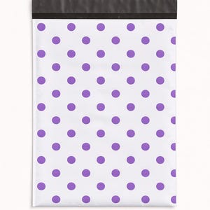 May include: White poly mailer with a repeating pattern of purple polka dots. The top edge has a black strip for sealing. This shipping bag is designed for mailing small items.
