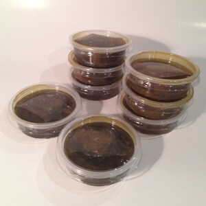 May include: A stack of eight clear plastic containers filled with a dark brown substance. The containers are stacked in a pyramid shape.
