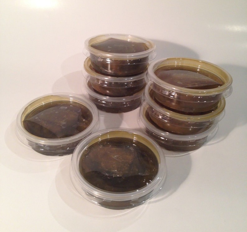 May include: A stack of eight clear plastic containers filled with a dark brown substance. The containers are stacked in a pyramid shape.