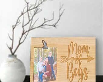May include: A wooden photo frame with a clip to hold a photo. The frame has the text "Mom of Boys" with an arrow and a heart. The photo in the frame shows a family of four.