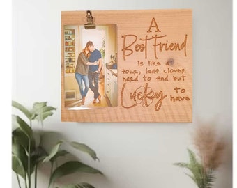 May include: A wooden picture frame with a photo of two people in a kitchen. The frame has an engraved message that reads "A Best Friend is like a four leaf clover hard to find but lucky to have".