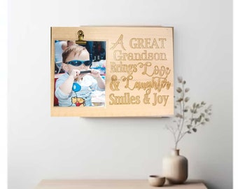 May include: A wooden picture frame with a photo of a young boy wearing sunglasses and a blue shirt. The frame has a quote engraved on it that reads "A GREAT Grandson Brings Love & Laughter Smiles & Joy".