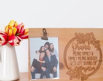 May include: Wooden photo frame with a clip to hold a photo. The frame has a floral design and the text "Ohana means family & family means nobody gets left behind or forgotten".