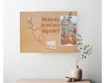 May include: A wooden sign with the states of Alabama and California carved into it. The sign also has the text "Even when we're far apart you're always in our hearts" and a photo of a person standing in a field of pumpkins.