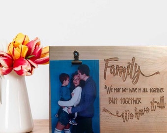 May include: A wooden photo frame with a clip to hold a photo. The frame has the words "Family" and "We may not have it all together, but together we have it all" engraved on it. The photo shows a family of three.