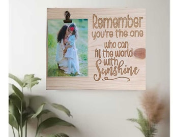 May include: A wooden photo frame with a picture of a mother and daughter. The frame has the text "Remember you're the one who can fill the world with Sunshine" engraved on it.