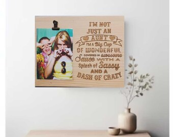 May include: A wooden photo frame with a picture of two women smiling. The frame has a quote engraved on it that reads "I'm not just an aunt, I'm a big cup of wonderful covered in awesome sauce with a splash of sassy and a dash of crazy."