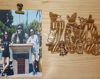 May include: A wooden plaque with a photo of a couple standing in front of a gorilla statue. The plaque is decorated with a laser-cut design of jungle animals and the word "Zoo".
