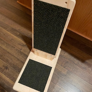 May include: A wooden cat scratching post with two scratching surfaces covered in dark green sisal rope. The post is freestanding and has a rectangular base.